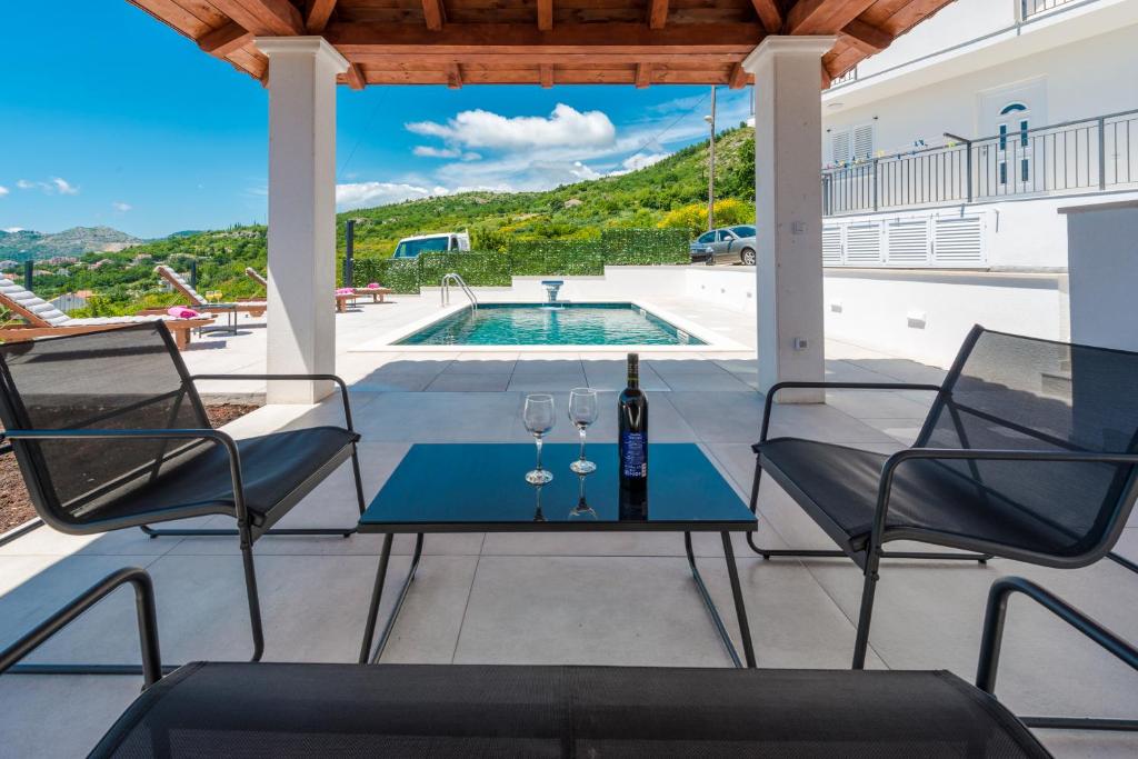 um pátio com 2 cadeiras e uma mesa com copos de vinho em Villa Vista em Mlini