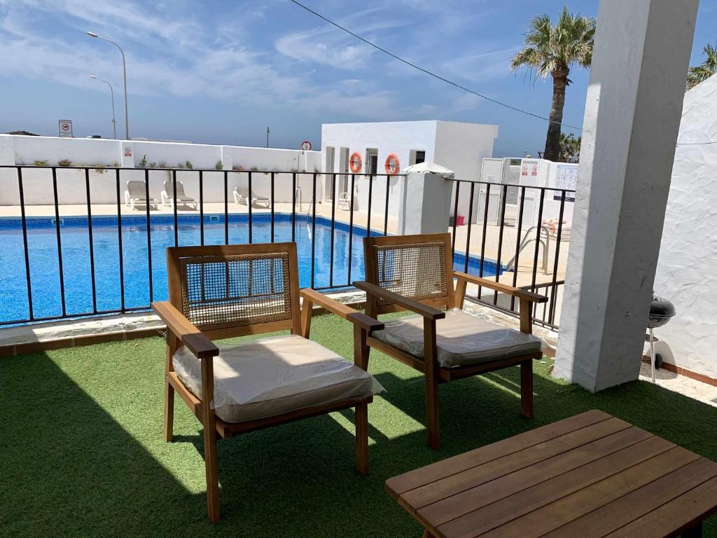 einen Balkon mit 2 Stühlen und einem Pool in der Unterkunft Urb Las Cañas I Apartamento F2 in Tarifa