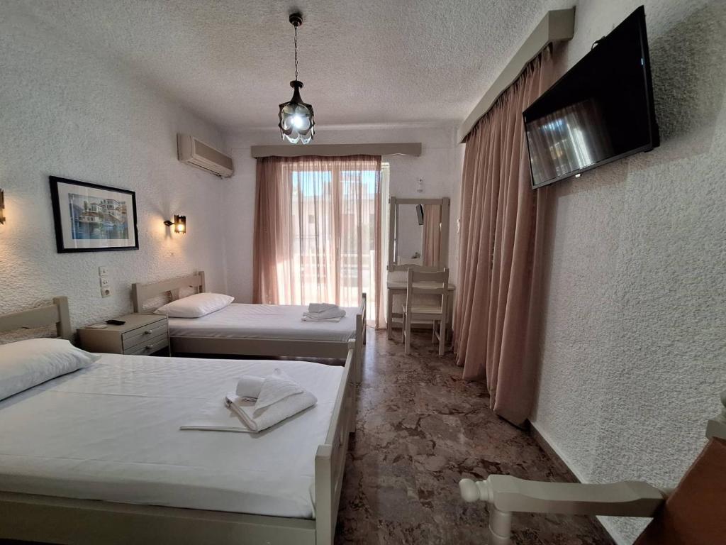 Una habitación de hotel con dos camas y un televisor. en Apartments by Evita's Resort, en Poros