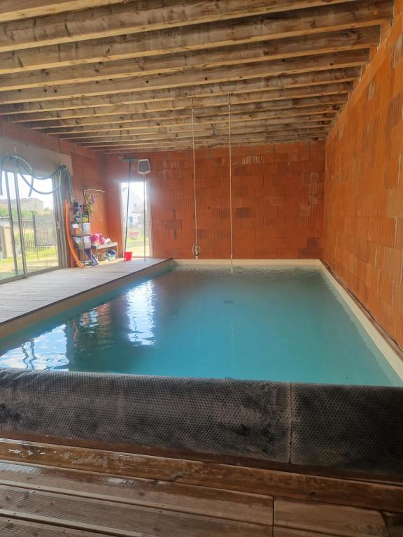 una piscina vacía en una habitación con una pared de ladrillo en L'écolodge de Laeti, en Lunéville