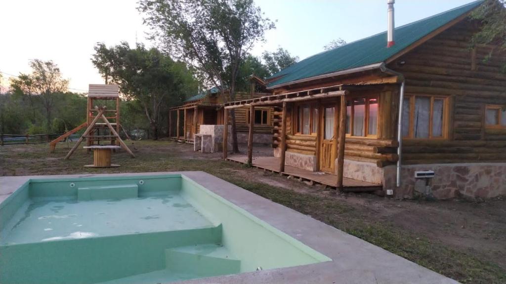a swimming pool in front of a log cabin at Sommerwind Cabañas in La Estancia