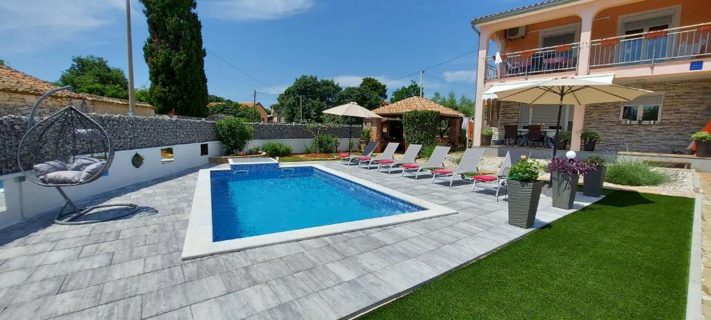 a swimming pool in a backyard with chairs and an umbrella at Apartments Katarina in Poreč