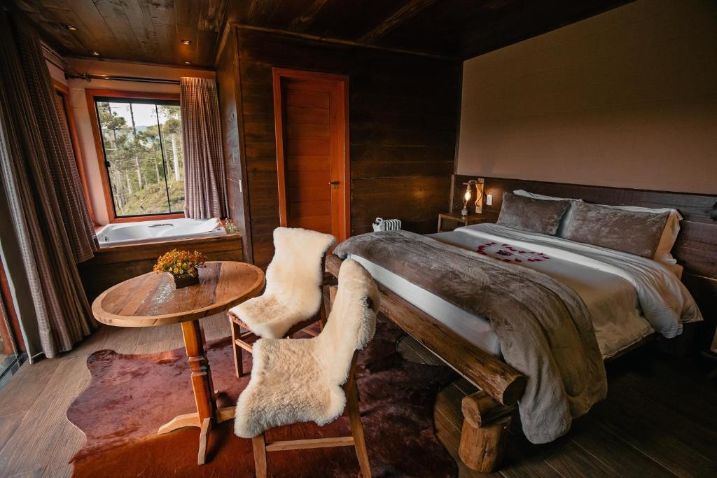 a bedroom with a bed and a table and a window at Sunset Serrano Chalés in Urubici