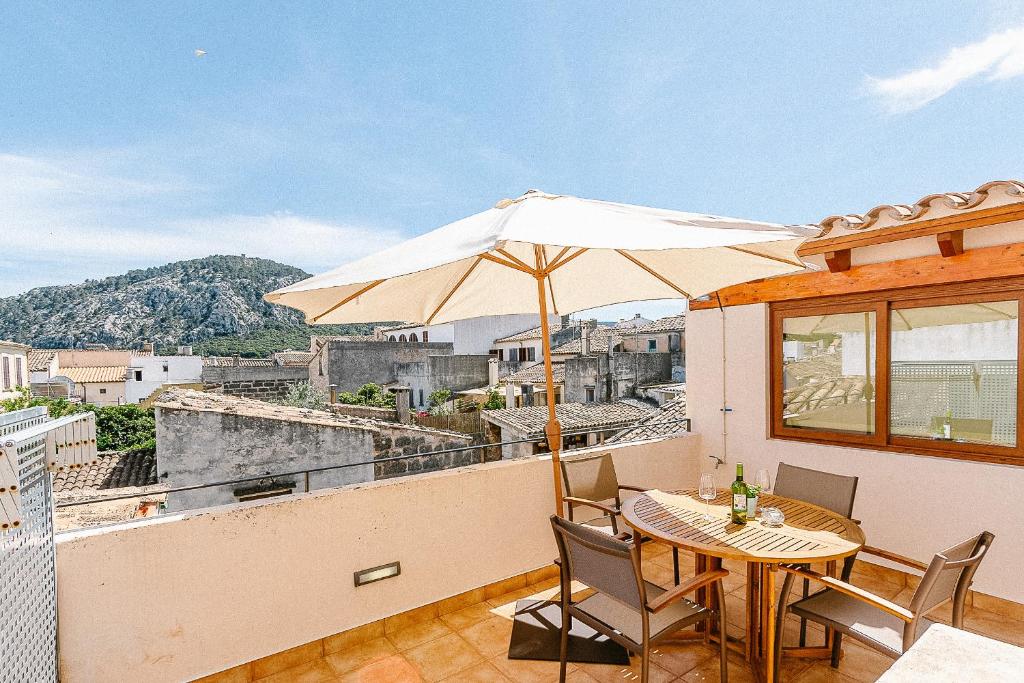 a patio with a table and an umbrella on a balcony at Townhouse with puig de María view by home villas 360 in Pollença