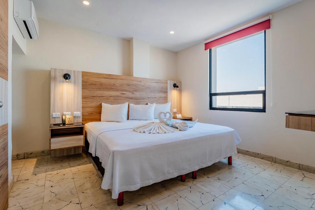 1 dormitorio con 1 cama blanca grande y ventana en Hotel Central Merida by Kavia, en Mérida