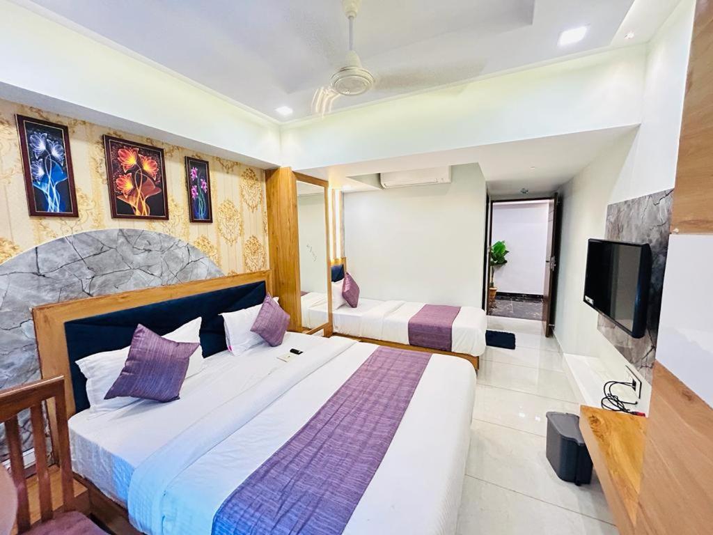 a bedroom with two beds and a flat screen tv at HOTEL RK FORTUNE in Ahmedabad