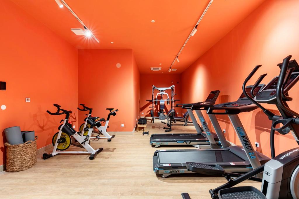 an orange gym with cardio machines and exercise bikes at Les Appartements de Grenoble in Grenoble