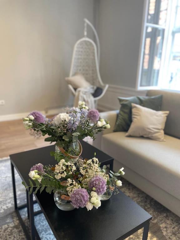 a living room with a vase of flowers on a table at Ferienwohnung Marzipan - im Herzen der Altstadt, historisches Gebäude mit modernem Ambiente, W-LAN in Lübeck