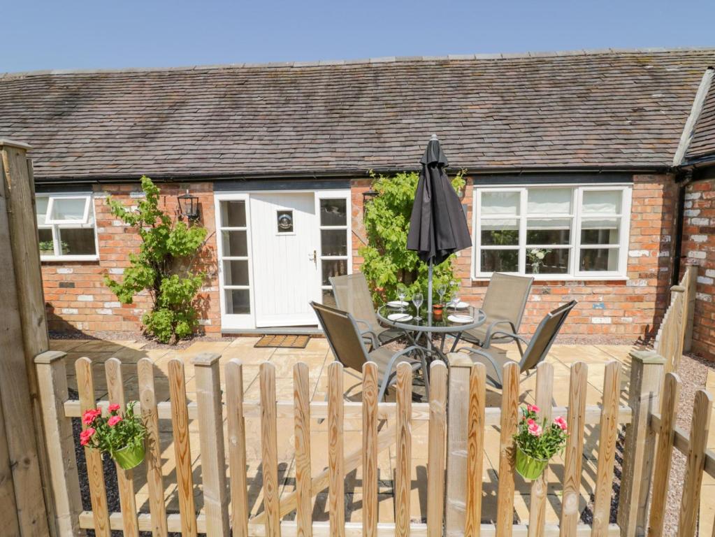 a house with a wooden fence and a table with an umbrella at The Nest in Nuneaton