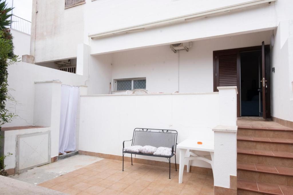 a white building with a chair on a patio at Casa Claire in San Vito lo Capo