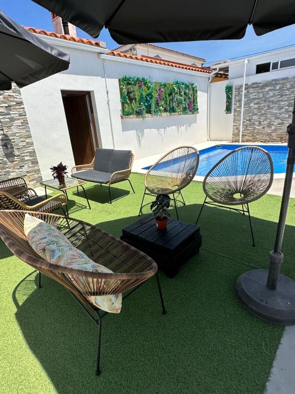 a group of chairs sitting on a lawn with an umbrella at Alojamiento El Miajon de los Castúos in Valdesalor