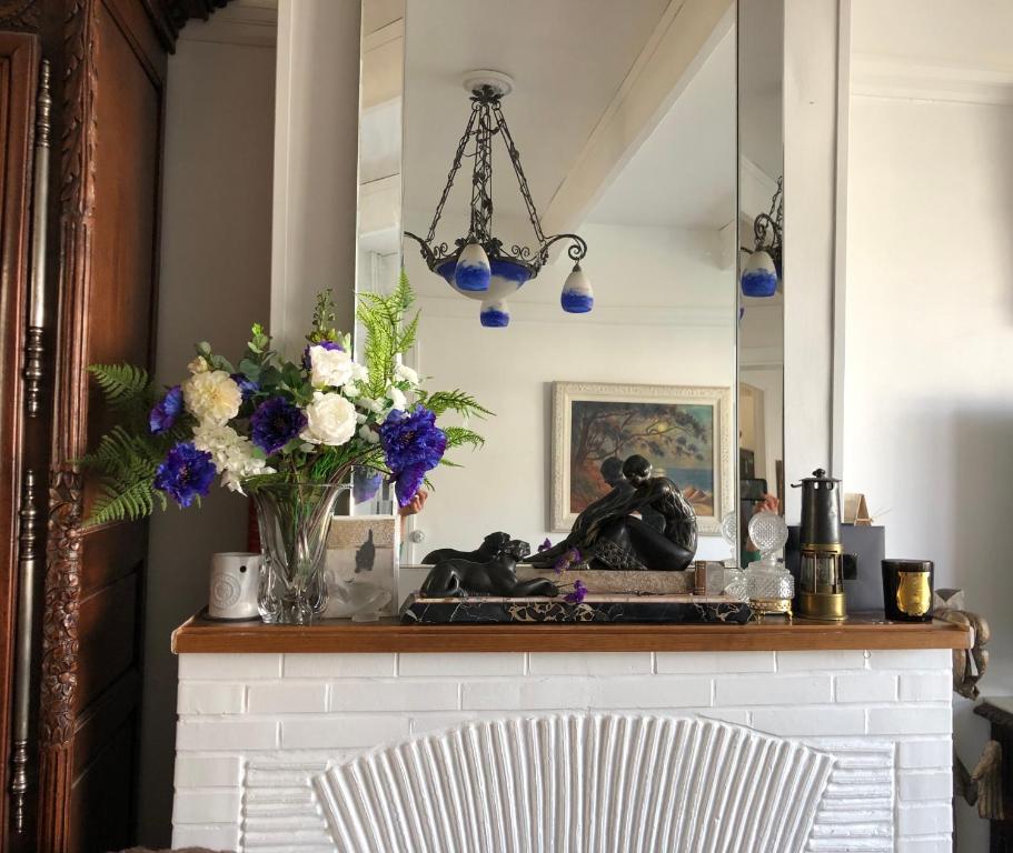 einen Kamin mit einer Vase aus Blumen und einem Spiegel in der Unterkunft VILLA EVA in Bray-Dunes