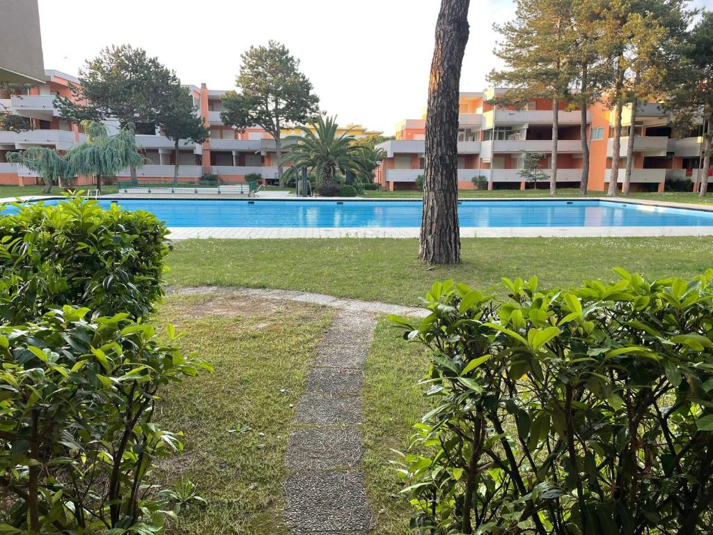 a swimming pool with a tree next to a building at Residence Solarium Qua in Bibione