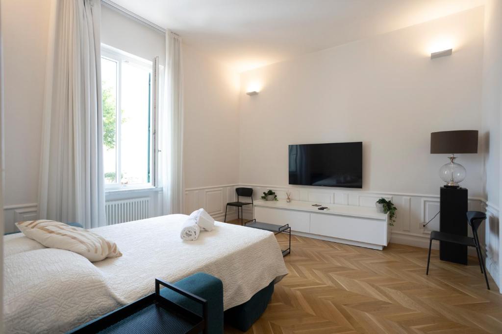 een witte slaapkamer met een bed en een flatscreen-tv bij SINONDA Luxury Apartment in Maiori