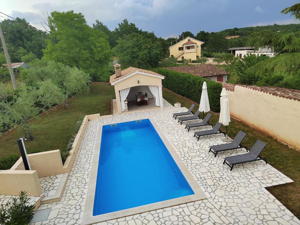 basen w ogrodzie z krzesłami i dom w obiekcie Villa Emilia w mieście Vižinada