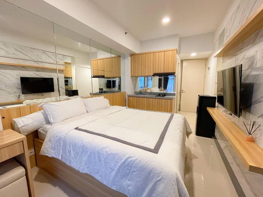 um quarto com uma grande cama branca e uma televisão em La Rosa at Benson Tower em Surabaya