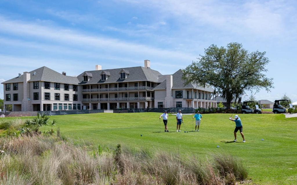 un groupe de personnes jouant au golf devant un grand bâtiment dans l'établissement Camp Creek Inn, à Seacrest