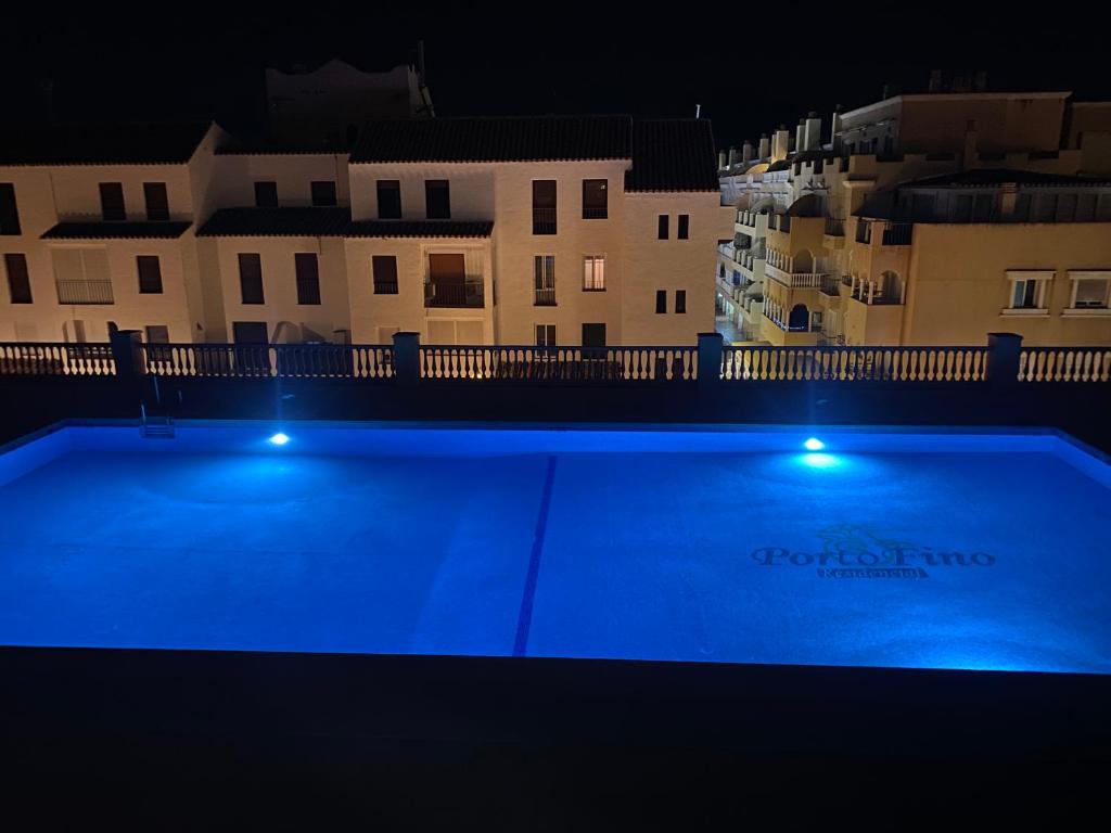 una piscina por la noche con edificios en el fondo en Apartamento Portofino Golf & Puerto Almerimar, en Almerimar