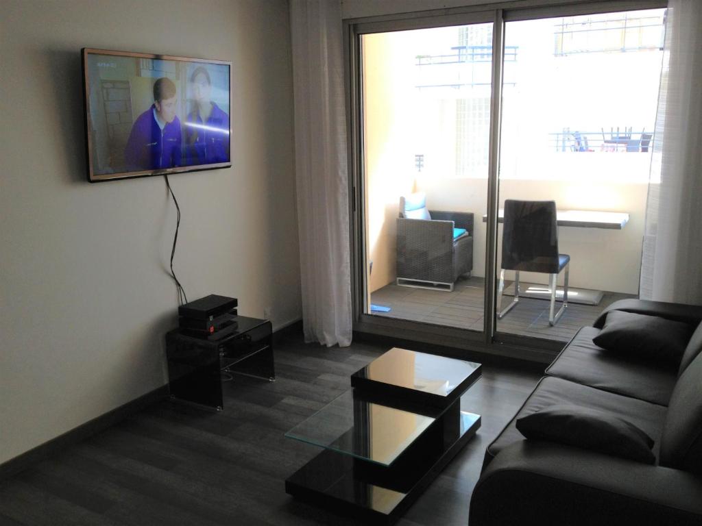 un salon avec un canapé et une télévision au mur dans l'établissement Juana, à Antibes