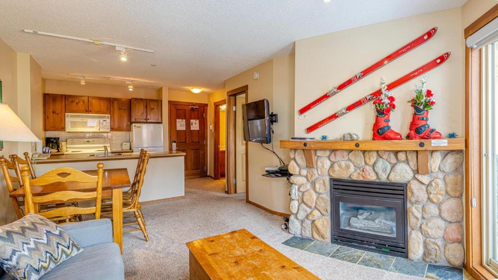 a living room with a fireplace and a kitchen at Fireside Lodge #315 By Bear Country in Sun Peaks