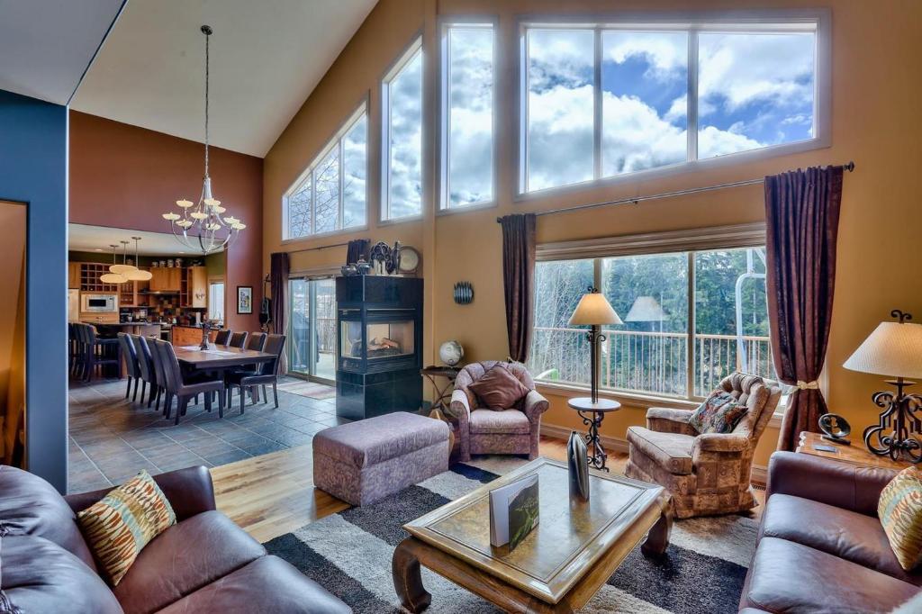 a living room filled with furniture and a large window at Soleil Chalet in Sun Peaks