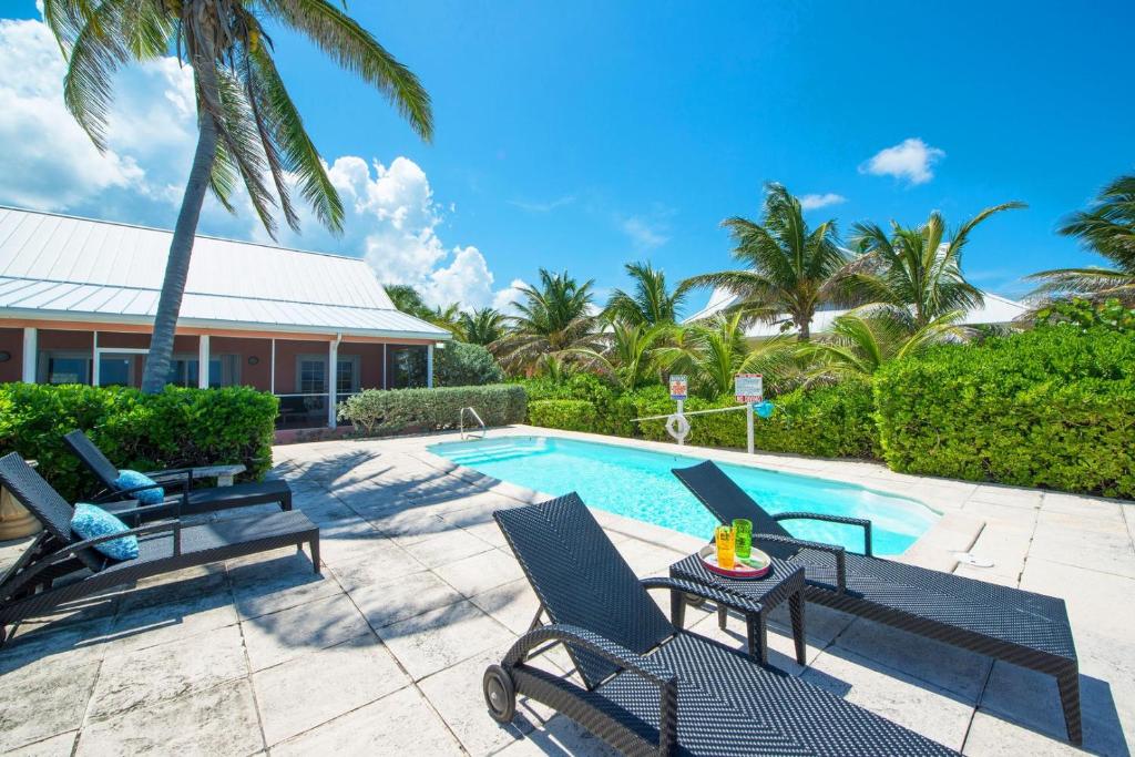 a swimming pool with chairs and a table next to a house at Cayman Dream by Grand Cayman Villas & Condos in Driftwood Village