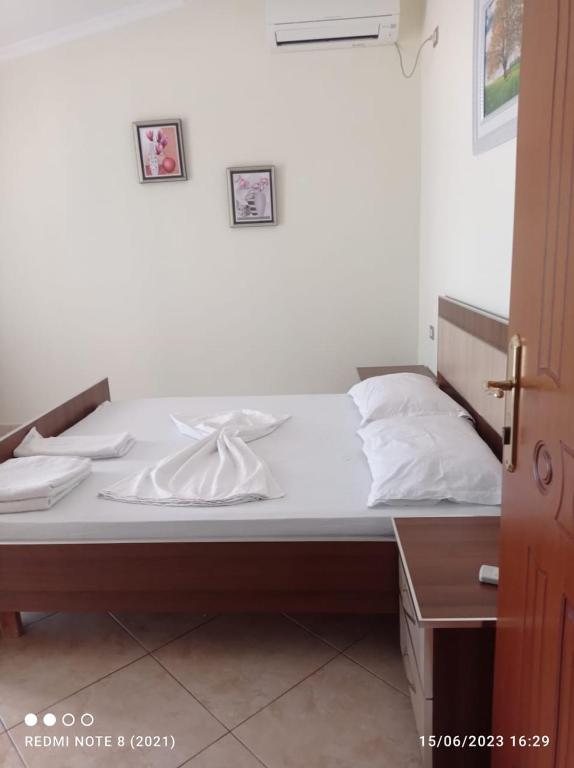 un letto con lenzuola bianche sopra in una stanza di Guesthouse Fatos Biti a Divjakë