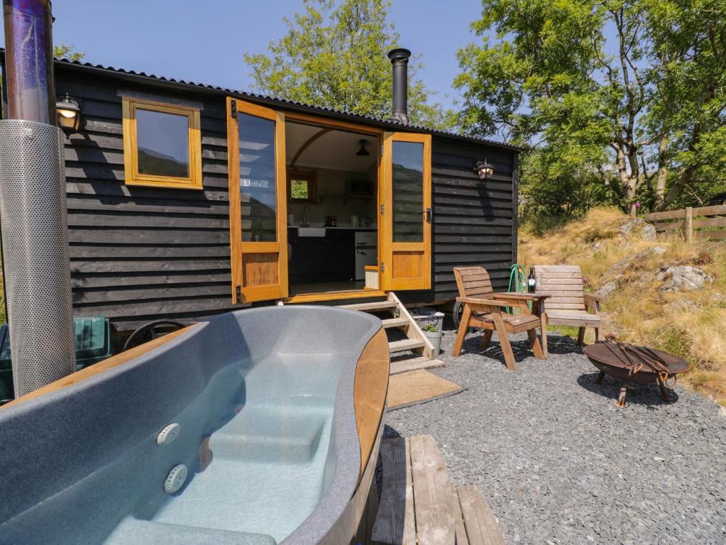 a tiny house with a swimming pool and a patio at Llethr - Shepherds Hut in Llanbedr