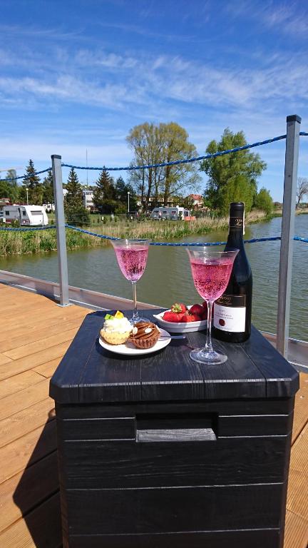 a table with two glasses and a bottle of wine at ARKA 2 - Houseboat w centrum Mielna, rower wodny, parking, Wi-Fi in Mielno