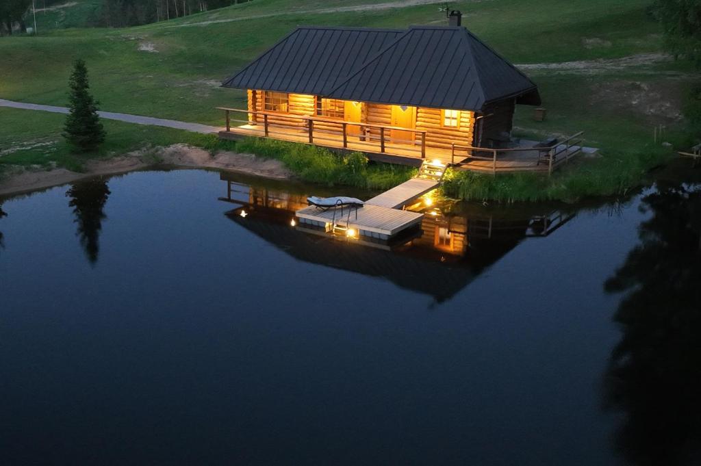 una cabaña de madera en un lago por la noche en Kütioru saunamajad, en Koloreino