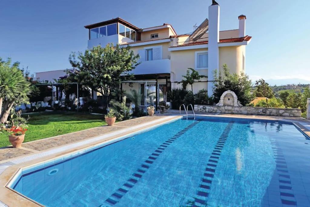 a villa with a swimming pool in front of a house at Crete's Hidden Treasure - Dream Villa with Pool and Majestic Olive Tree Views in Skalánion