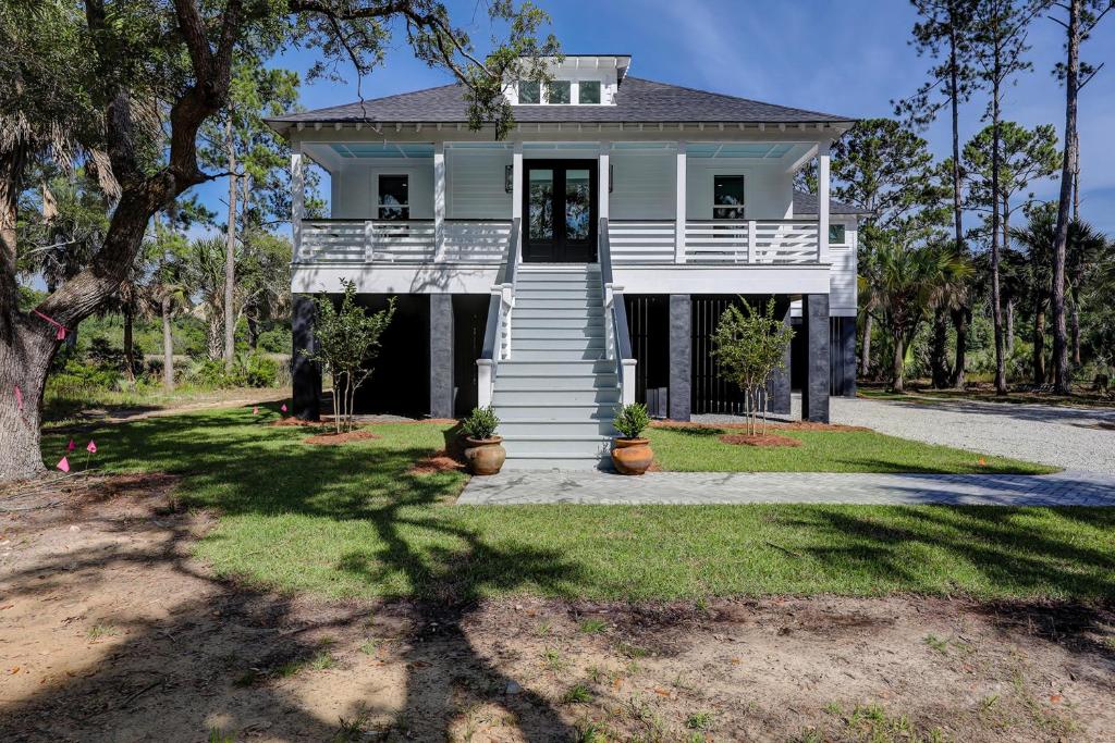 a white house with a porch and a tree at Nature's Touch in Edisto Island