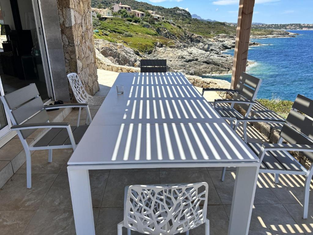 Villa coucher de soleil sur mer في ألغاجولا: طاولة بيضاء وكراسي على فناء مع المحيط