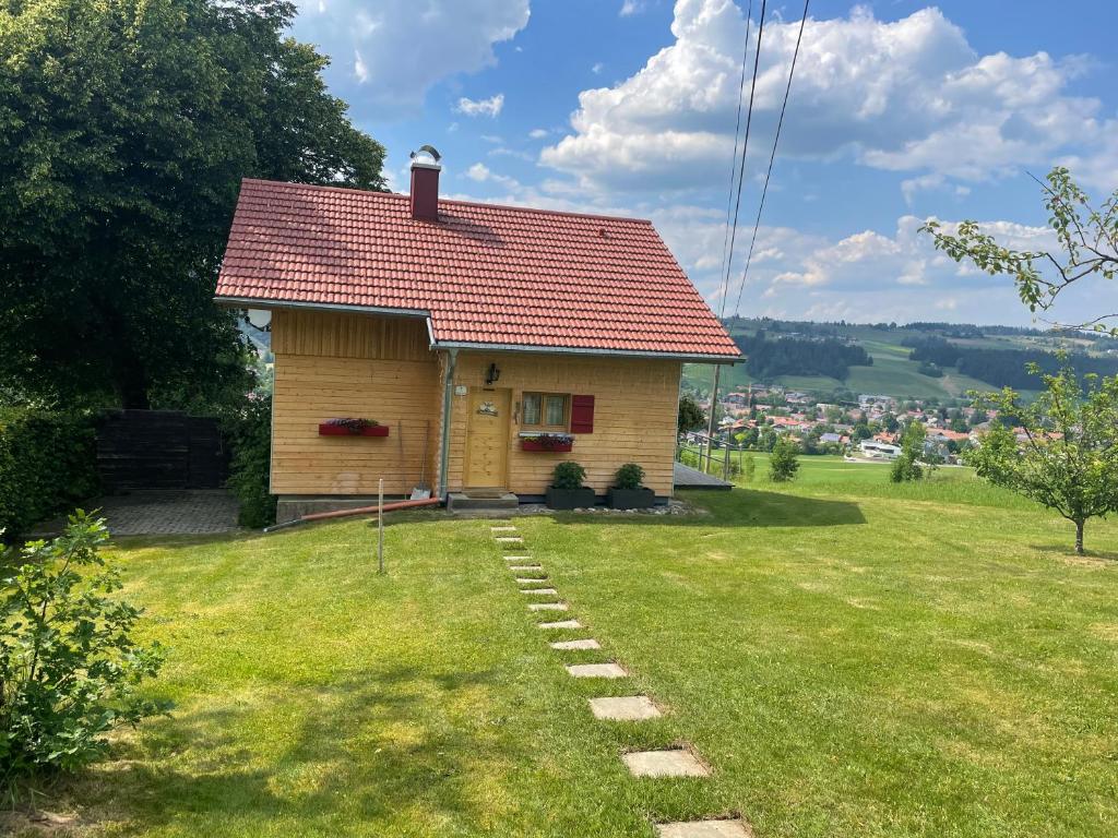 una pequeña casa amarilla con techo rojo en una colina en Ferienhaus Talblick en Weiler-Simmerberg