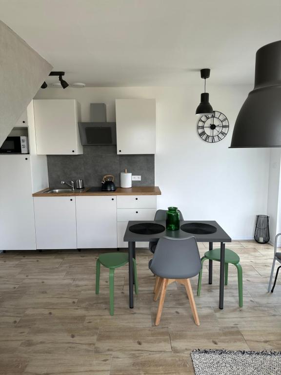 a kitchen with two tables and green chairs at Apartamenty Bosmańska in Rusinowo