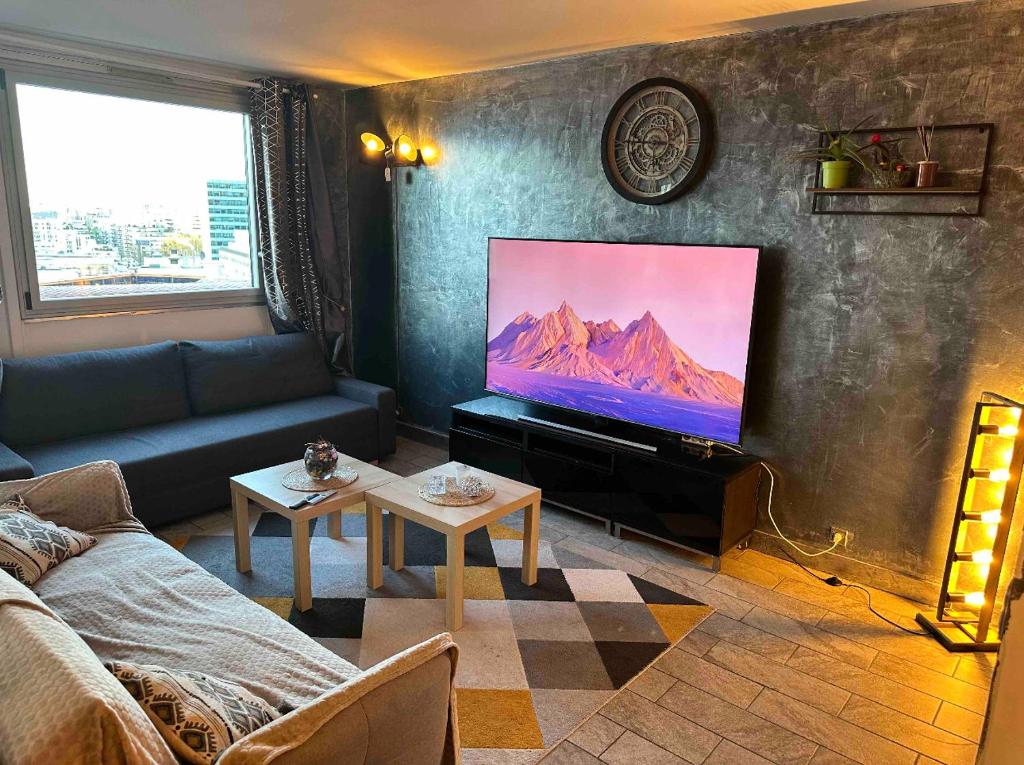 ein Wohnzimmer mit einem Sofa und einem Flachbild-TV in der Unterkunft Grand appartement proche métro quartier la defense in Courbevoie