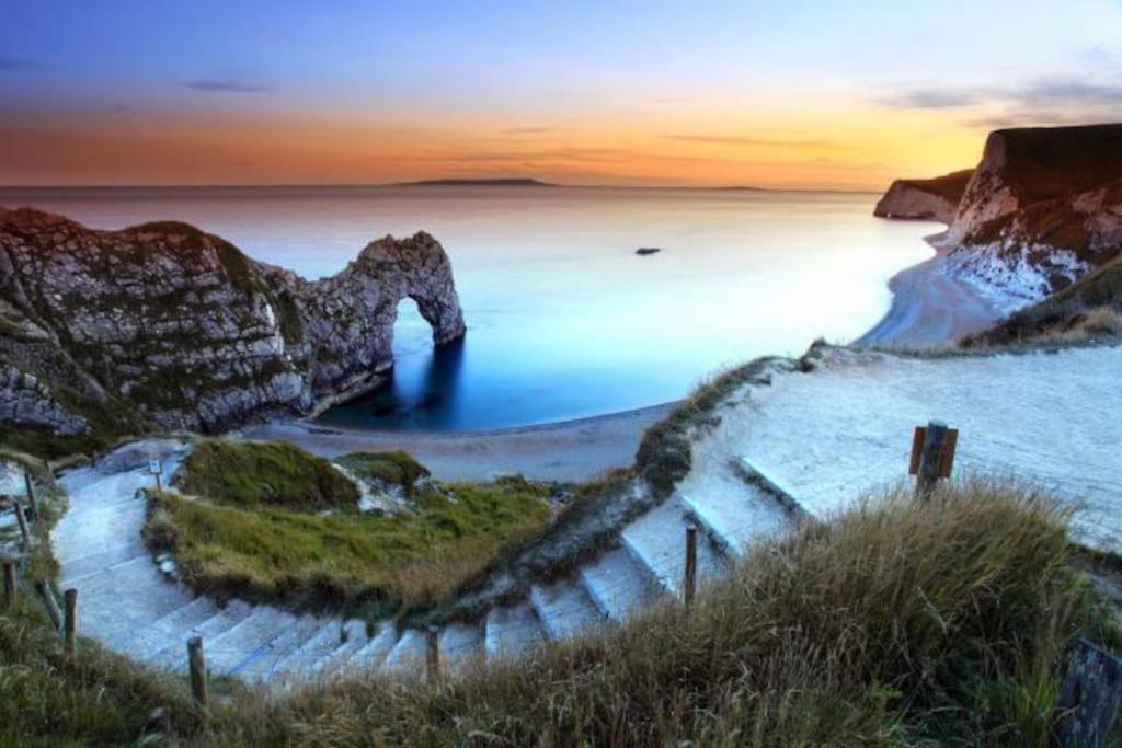 een uitzicht op een strand bij zonsondergang met de oceaan bij 2-6 guests Holiday Home in Durdle Door in Wareham