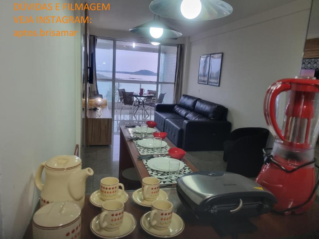 a living room with a table with cups and a blender at Apartamento Frente para o Mar - Varandão com Blindex - Vista Total para o Mar - 1 Suite e mais 2 Quartos-Ar Condicionado - 2 Vagas - BEIRA MAR - 70 metros da Praia ,TVS SMART GERAL -WI-FI -DISNEY PLUS-STARMAX-NETFLIX - PRIME VIDEO -PORTARIA 24 HORAS in Guarapari