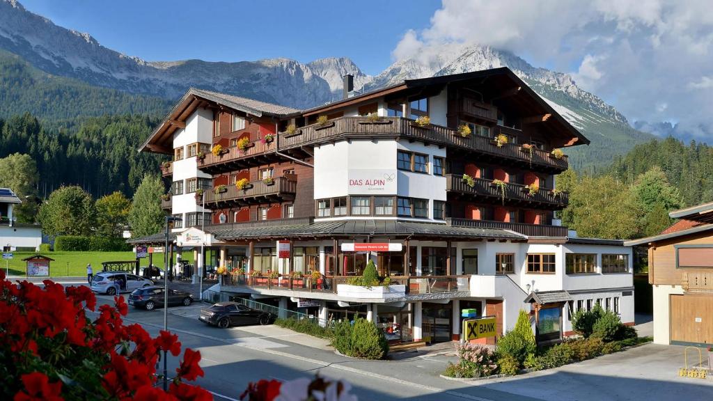 a large hotel with a mountain in the background at Das Alpin - Hotel Garni Guesthouse in Scheffau am Wilden Kaiser