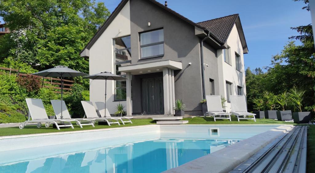 uma casa com piscina em frente a uma casa em AQUA SOLAR APARTMANHÁZ em Miskolc