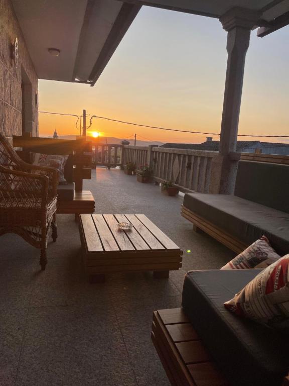 un patio con sofás, mesas y vistas a la puesta de sol en Casa Arxon, en Meaño