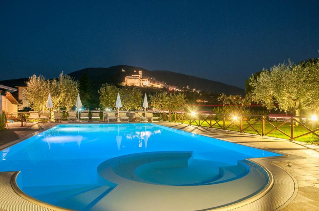 a large swimming pool in a resort at night at Agriturismo La Panoramica in Assisi