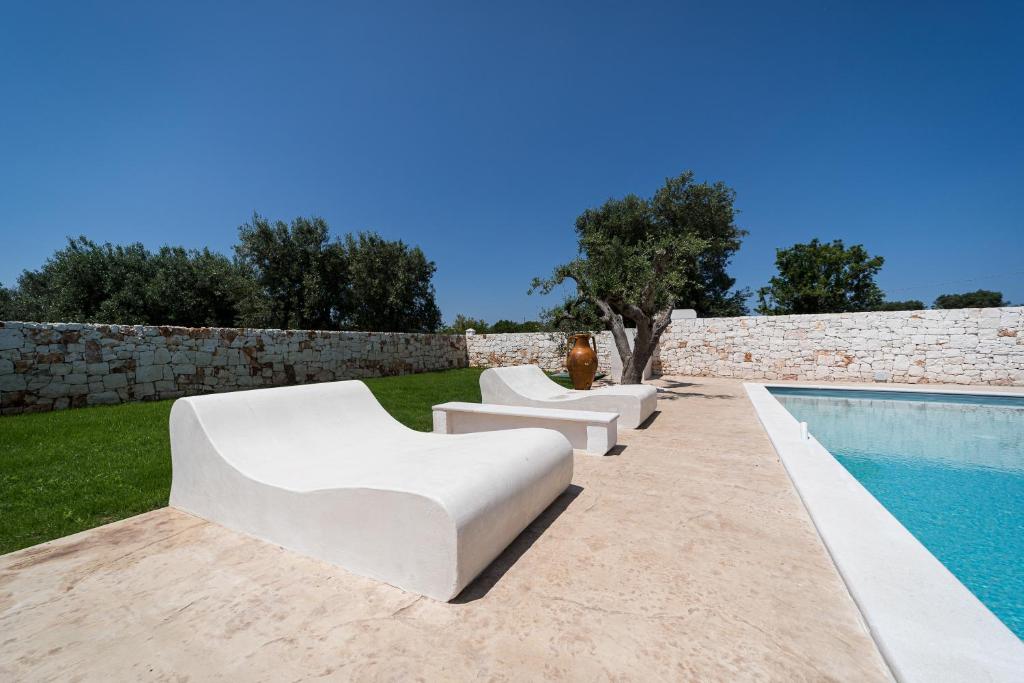 un grupo de sillas blancas sentadas junto a una piscina en Villa Bianca - Private swimming pool - Center - by ClickSalento, en Ostuni