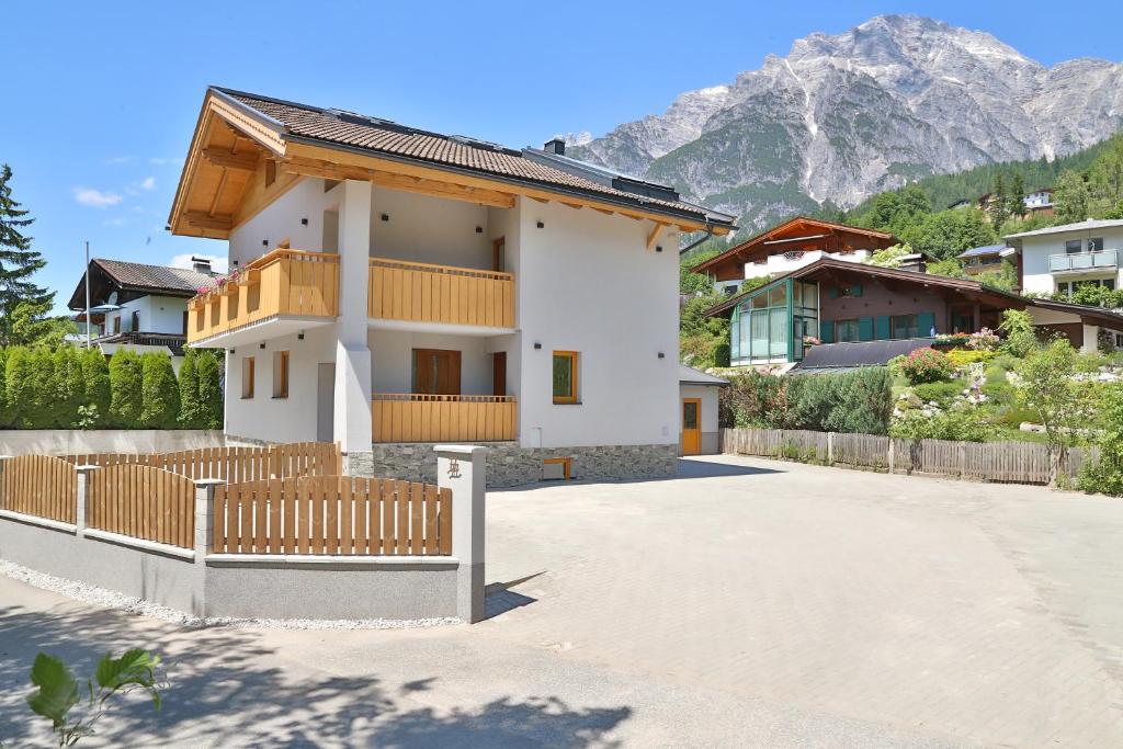 a white house with a fence and mountains in the background at Apartment SB77 Leogang in Leogang