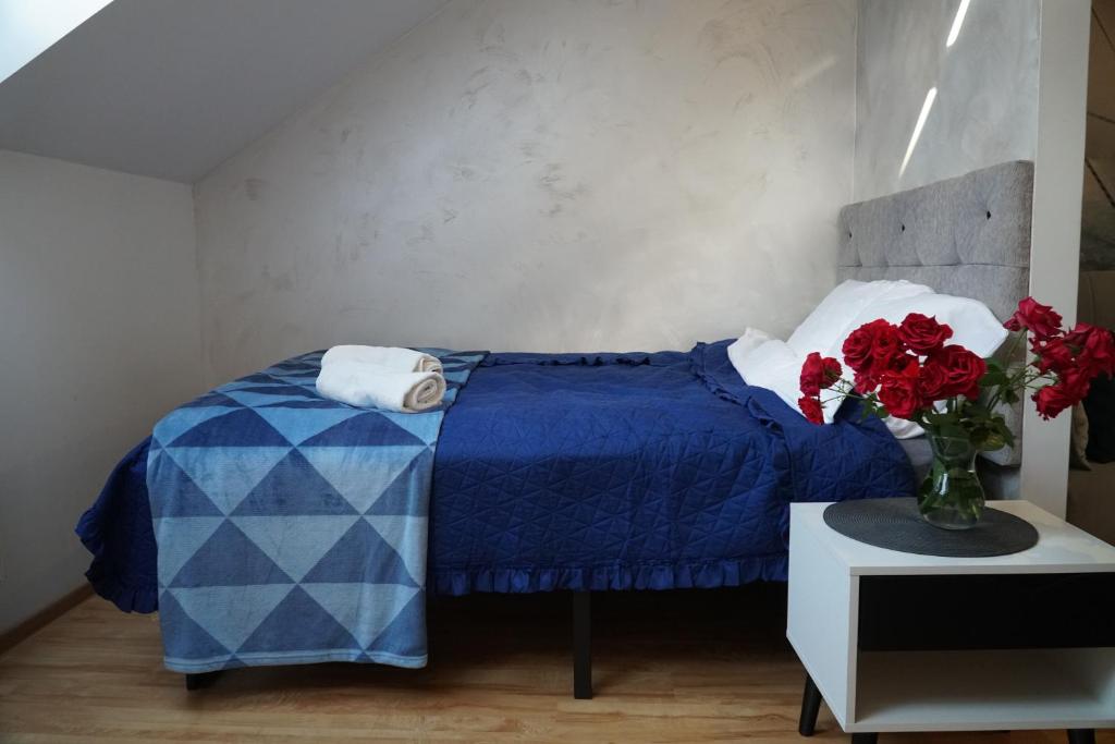 a bedroom with a blue bed and a vase of red roses at Apartament w centrum OSTOYA 1 in Ełk