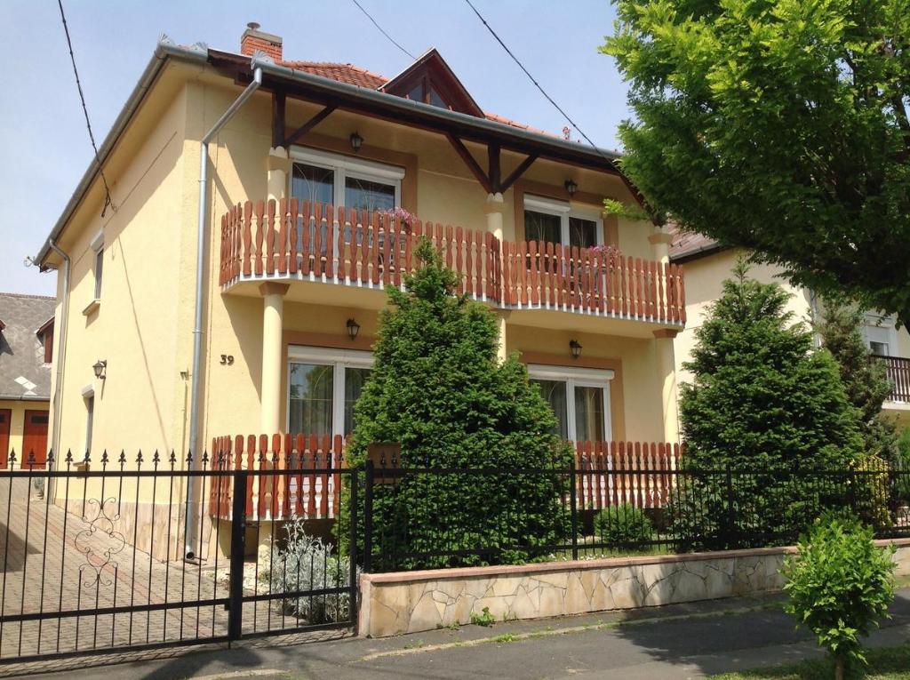 Casa amarilla con balcón y árboles en Apartment Villa Attila, en Hévíz