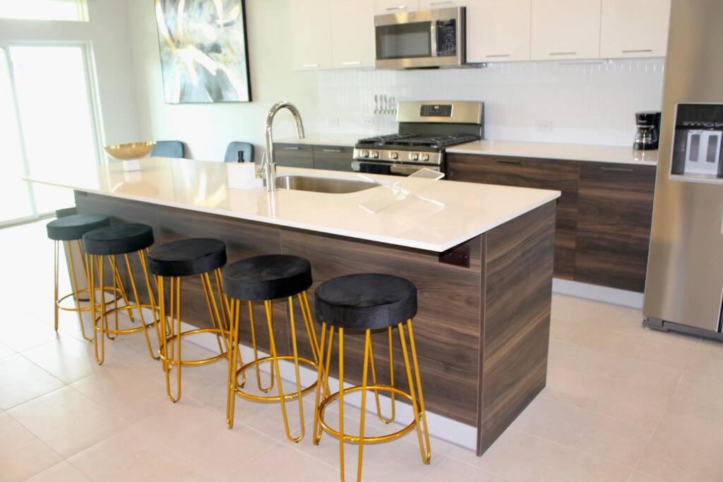 a kitchen with a sink and bar stools at Modern Minimalist Luxury Retreat in Houston