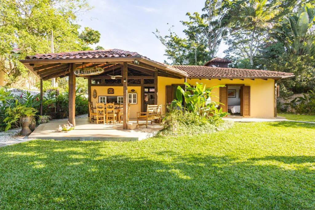 een geel huis met een tafel en stoelen in een tuin bij Casa na Barra do Sahy - Beira Mar - Litoral Norte SP in São Sebastião
