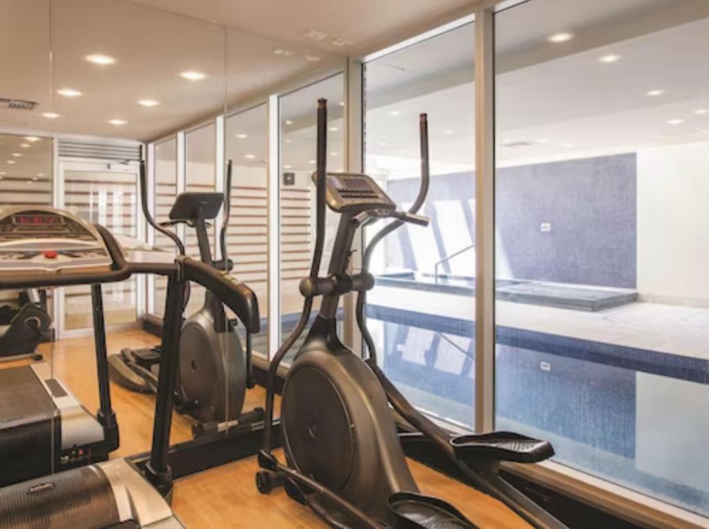 a gym with cardio machines and a swimming pool at Glenelg resort style beachside apartment in Glenelg