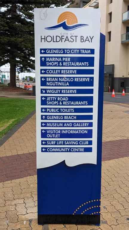 a sign for the houstoniest bay sign in front of a building at Glenelg resort style beachside apartment in Glenelg